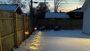 Patio nevado con una fila de luces exteriores que crean diseños como estrellas en el suelo.