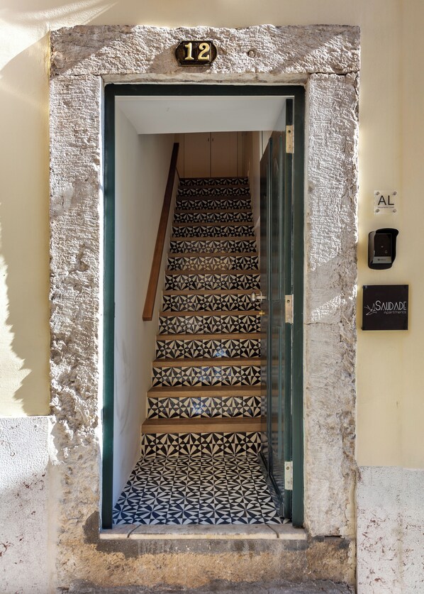 Un escalier recouvert de carreaux décorés mène à une porte portant le numéro 12.