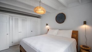 Une chambre à coucher avec un grand lit, un luminaire suspendu, un élément de décoration circulaire fixé au mur et une table de chevet en bois.