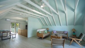 Un loft spacieux avec de hauts plafonds, un coin repas, un canapé et un fauteuil.