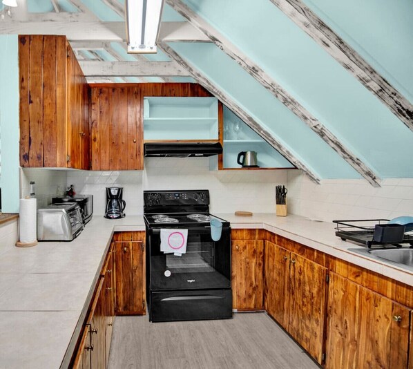 Una cocina con armarios de madera, una estufa negra y una encimera blanca.