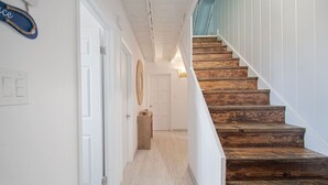 A staircase with wooden steps leading to a landing, white walls, and a light fixture above the door.