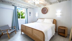 A bedroom with a large bed, a chair, a nightstand, and a ceiling fan.
