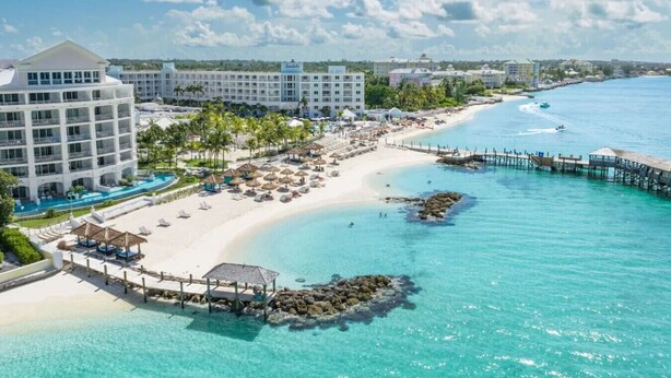 A resort with a beach, a pool, and a pier.