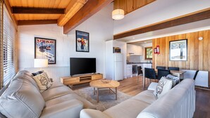 Un salon moderne avec un téléviseur, des canapés et un coin repas.