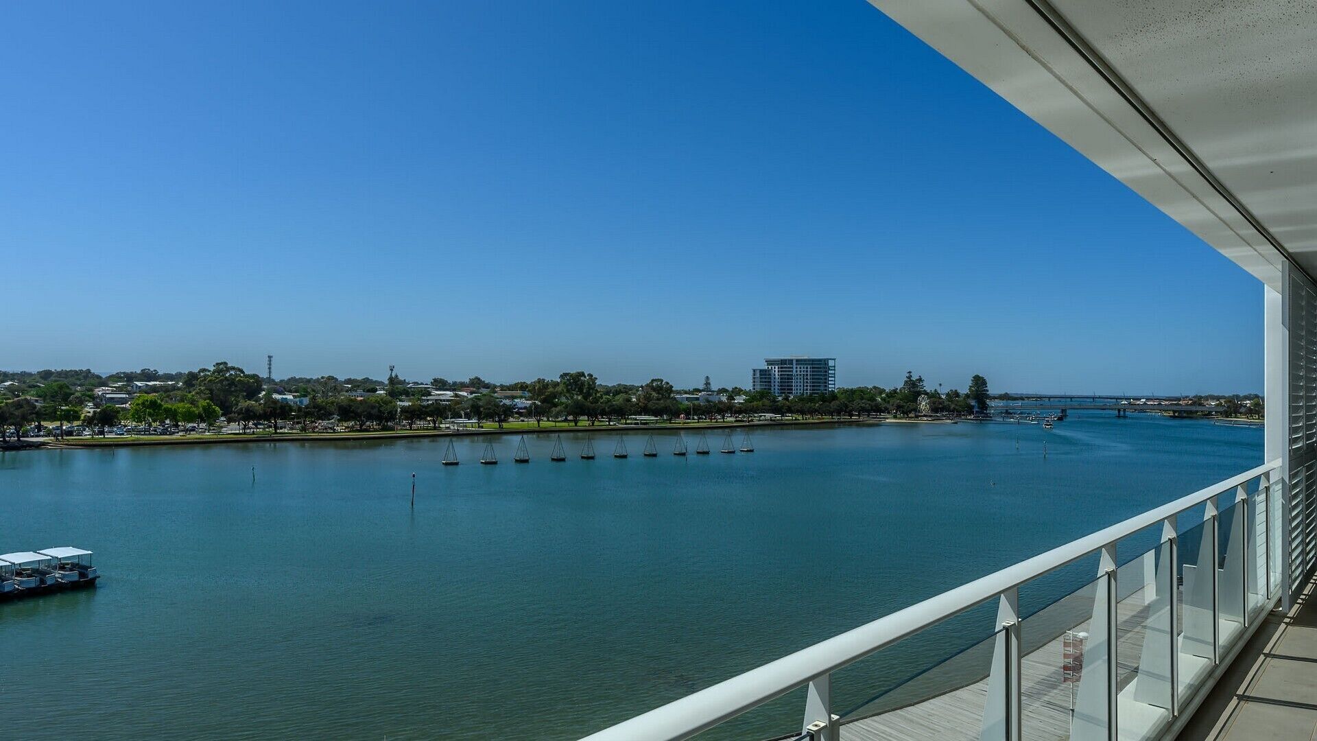 Une vue sur le front de mer depuis un balcon, avec un ciel dégagé, une rivière paisible et un pont situé au loin.