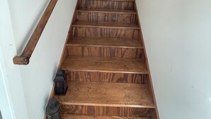 A wooden staircase with a handrail on one side and a lantern on the other.