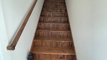 A wooden staircase with a handrail on one side and a lantern on the other.