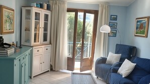 A living room with a sofa, a cabinet, a table, and a balcony. - An oasis of relaxation, in a dreamy sea. Beautiful view of the sea mountain and village  (Cala Gonone)