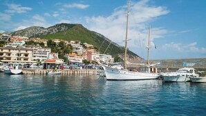 A marina with several boats docked, a mountainous backdrop, and buildings along the waterfront. - An oasis of relaxation, in a dreamy sea. Beautiful view of the sea mountain and village  (Cala Gonone)
