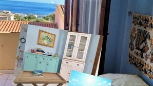 A room with a view of the sea, a dining area with a table and chairs, a kitchen with cabinets, and a bed with a painting. - An oasis of relaxation, in a dreamy sea. Beautiful view of the sea mountain and village  (Cala Gonone)