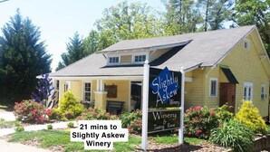 A yellow building with a sign reading "Slightly Askew Winery" and a sign indicating "21 mins to Slightly Askew Winery."