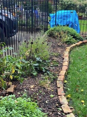 Stroll through the serene garden, surrounded by lush plants and a brick pathway.