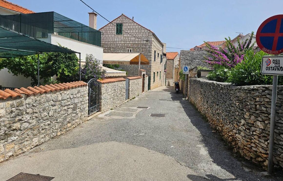 Una calle estrecha con paredes de piedra y un edificio con techo de tejas.