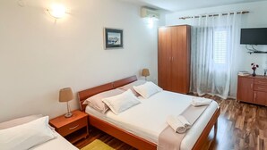 A neatly arranged hotel room with a bed, bedside tables, a wardrobe, a television, and a window with curtains. - Amazing apartment in Supetar with lake view (Supetar)