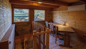 Uma cabana de madeira com área de jantar, escada e vista para o exterior.