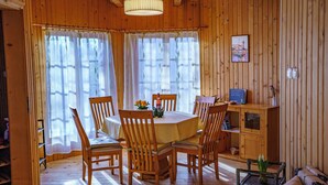 Um interior de madeira com uma mesa de jantar redonda, cadeiras, um sofá e um pequeno armário.