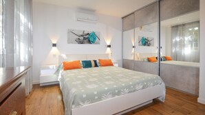A bedroom with a bed, bedside tables, a dresser, and a large mirror. - Amazing home in Cervione (Cervione)