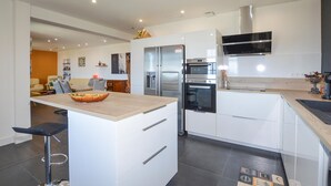 A modern kitchen with white cabinetry, stainless steel appliances, and a wooden island. - Amazing home in Cervione (Cervione)