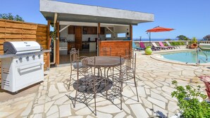 A patio with a grill, outdoor seating, a pool, and a view of the ocean. - Amazing home in Cervione (Cervione)