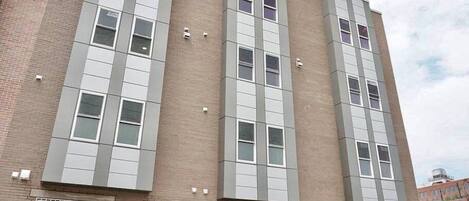 Un immeuble à plusieurs étages, doté d’une façade en briques, de grandes fenêtres et d’un toit plat.