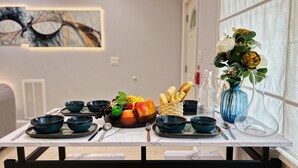 Ett matbord dukat med skålar, frukt, bröd och en vas med blommor.