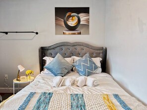 A neatly made bed with a striped bedspread, a tufted headboard, and two decorative pillows. - Ramblei near Chinatown & CenterCity | 1Bedroom-B (Philadelphia)