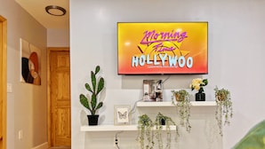 Ett modernt vardagsrum med en platt-TV på väggen som visar programmet ”Morning Time Hollywood”.