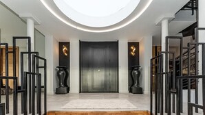 A modern entrance with a dark wooden door, two black vases, and a circular skylight. - Beautiful home in Sète (Sète)