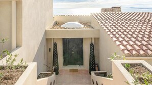 A building with a tiled roof, a central entrance with a door, and a small garden area with plants. - Beautiful home in Sète (Sète)