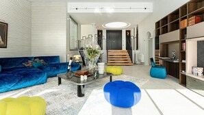 A modern living room with a blue sofa, a glass coffee table, and a bookshelf. - Beautiful home in Sète (Sète)