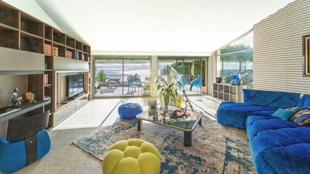 A modern living room with a blue sofa, a yellow ottoman, and a glass coffee table. There are bookshelves and a television on the left side. - Beautiful home in Sète (Sète)