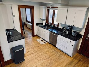A kitchen with white cabinets, a black countertop, and a stainless steel sink. - #41- Available 12/8! - sleeps 14 (Southington)