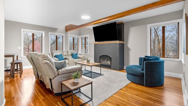 A modern living room with a fireplace, leather sofas, a blue armchair, and large windows. - #30 - Spacious & Cozy! (Southington)
