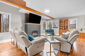 A modern living room with leather sofas, a fireplace, a flat-screen TV, and a wooden bookshelf. - #30 - Spacious & Cozy! (Southington)