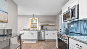 A modern kitchen with white cabinets, a stainless steel range, a microwave, and a herringbone-patterned backsplash. - #30 - Spacious & Cozy! (Southington)