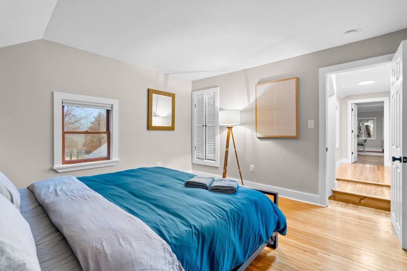 Un dormitorio con cama, ventana, lámpara y puerta que da a otra habitación.