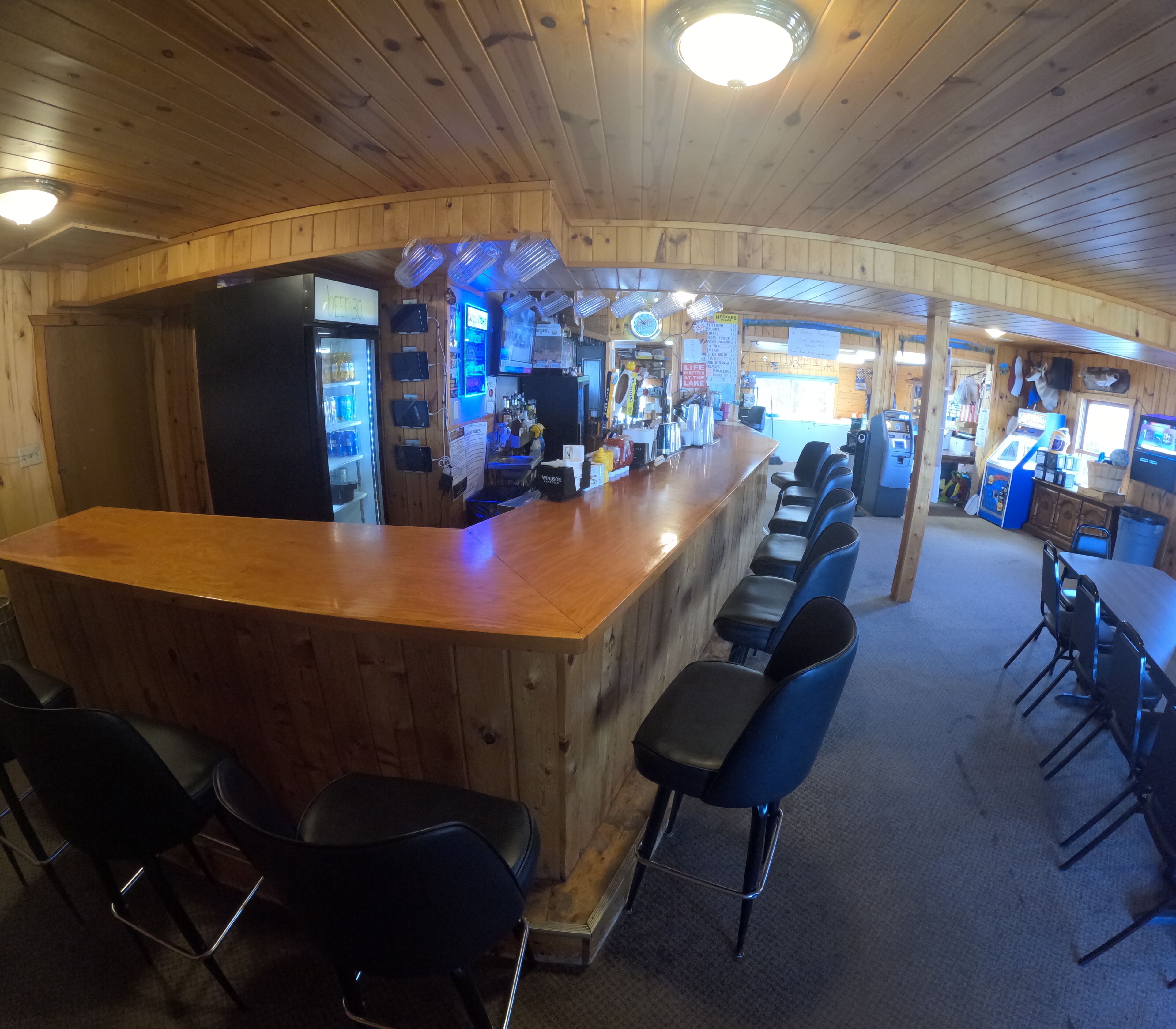 Un espace bar avec un comptoir en bois, des tabourets de bar noirs et un panneau lumineux au néon.