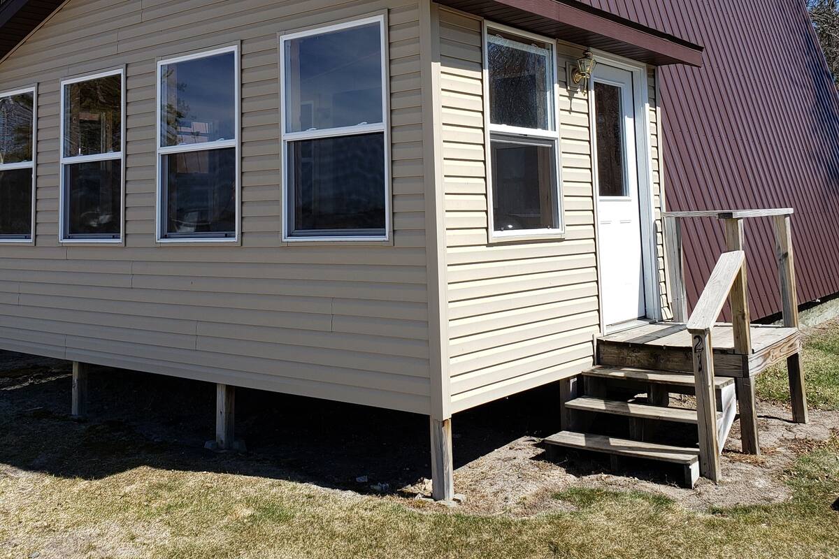 Une maison à deux étages avec un porche à l’avant et un petit escalier menant à l’entrée.