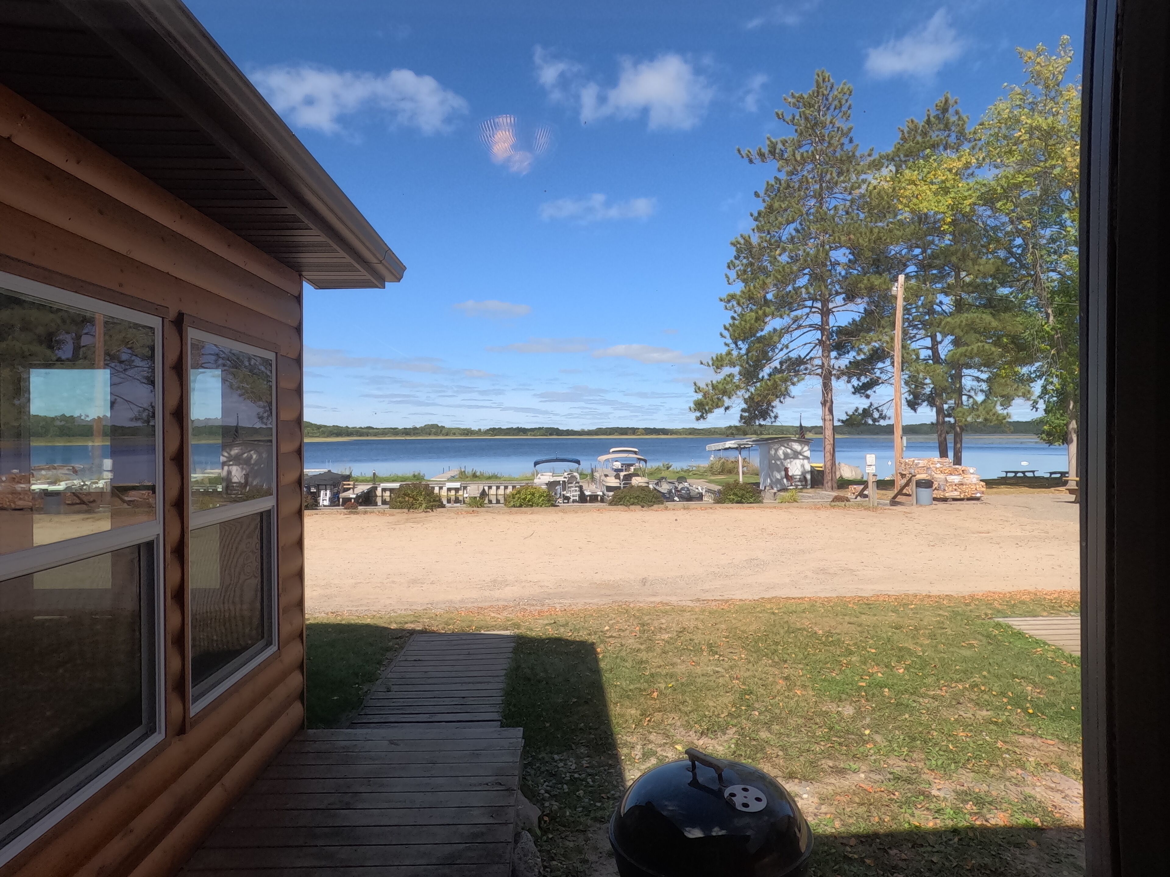 A wooden cabin with a view of a lake and parked vehicles.