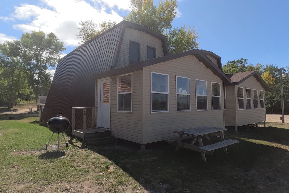 Une maison à deux étages dotée d’un patio couvert, d’un barbecue et d’une table de pique-nique.