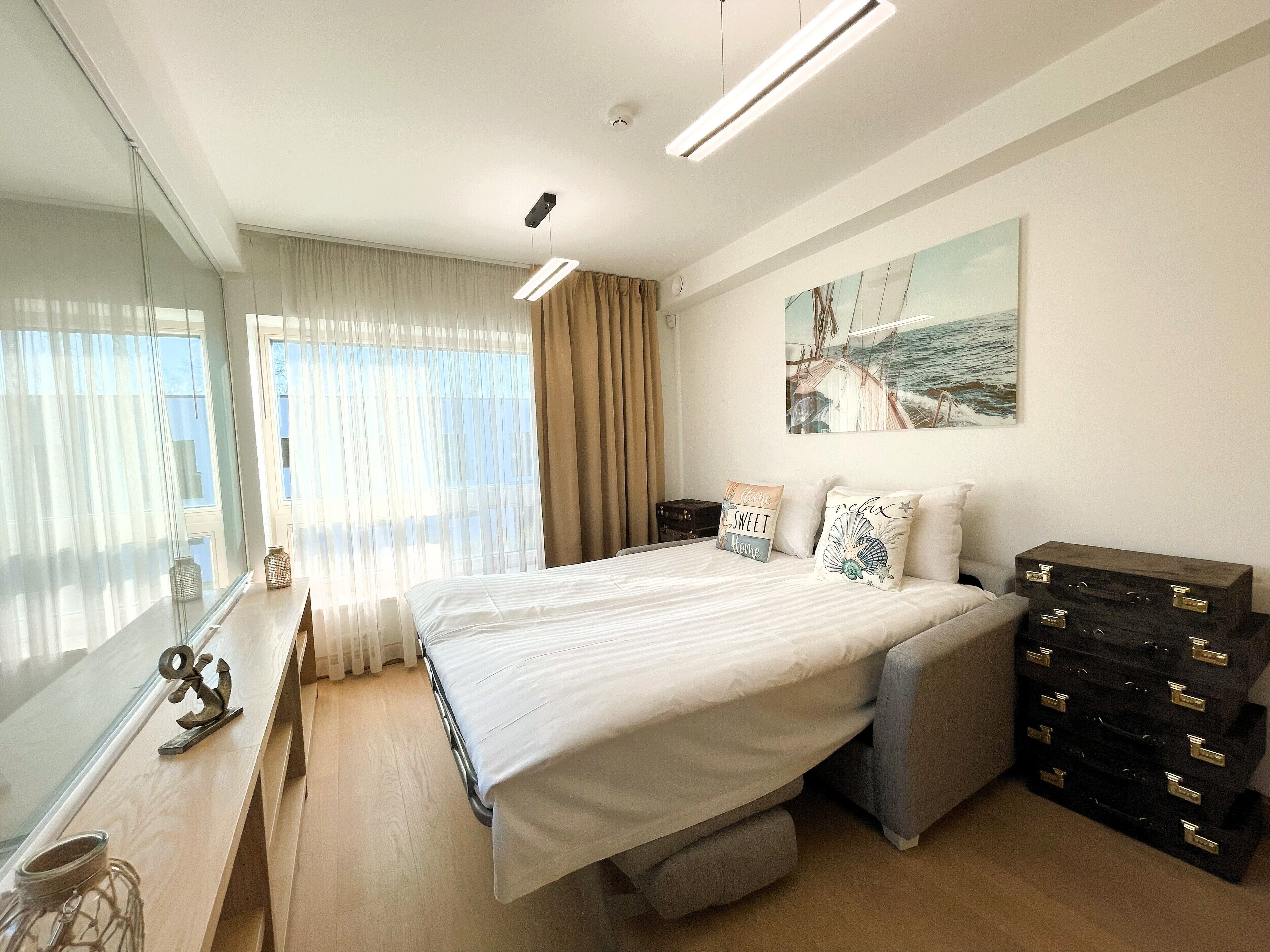 Un dormitorio moderno con una cama grande, mesitas de noche, un aparador, un espejo y un cuadro en la pared.