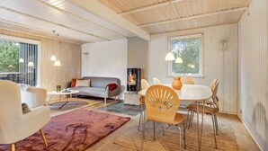 Ein gemütliches Wohnzimmer mit Kamin, einem Essbereich mit rundem Tisch und Stühlen sowie einer Couch mit roter Decke.