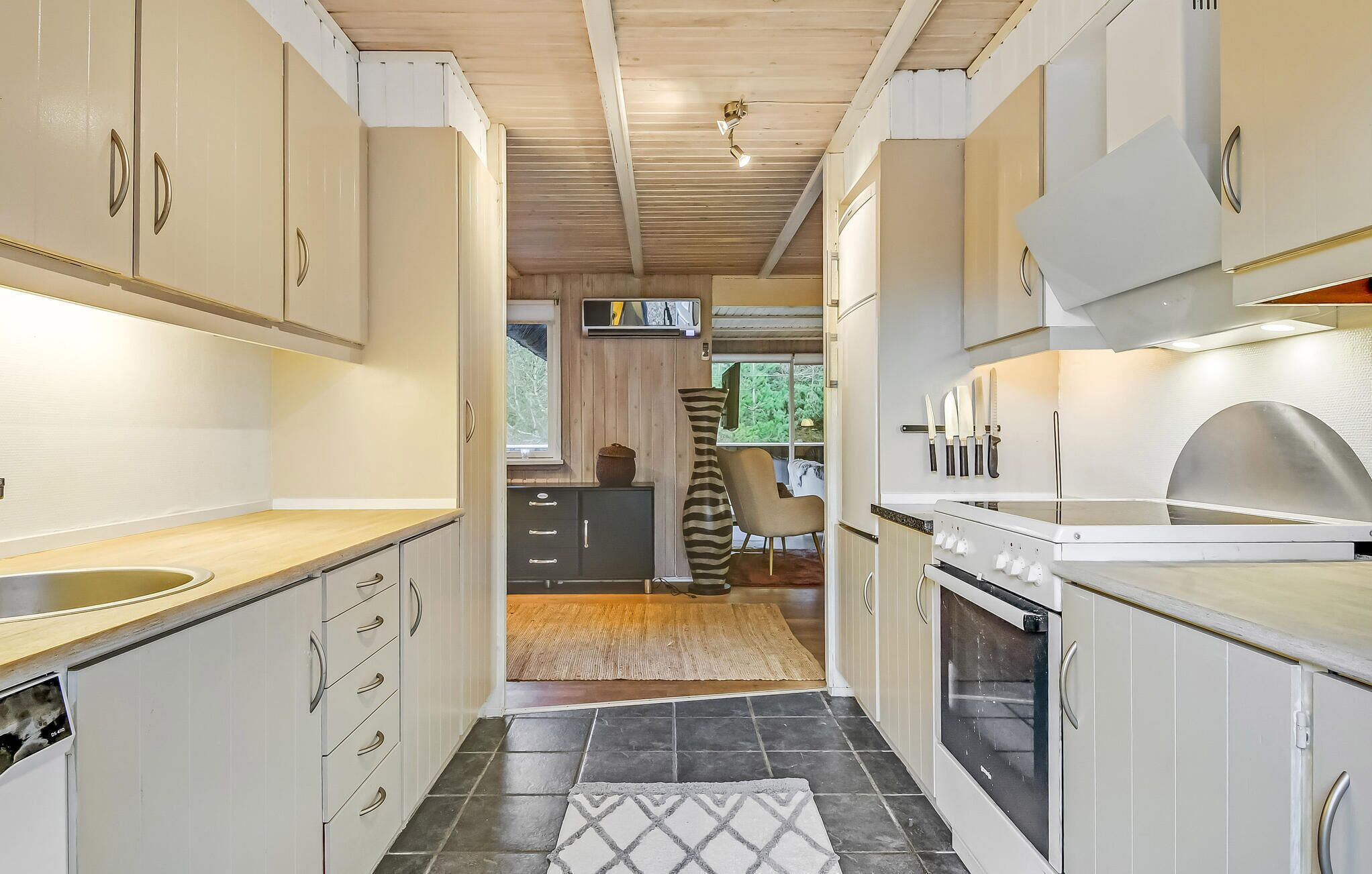 A modern kitchen with white cabinets, a built-in oven, and a large window providing natural light.