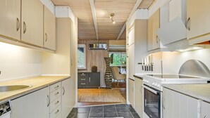 Eine moderne Küche mit weißen Schränken, einem eingebauten Ofen und einem großen Fenster, das für natürliches Licht sorgt.