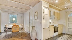 Eine moderne Küche mit weißen Schränken, einem großen Fenster und einem Essbereich mit Tisch und Stühlen.
