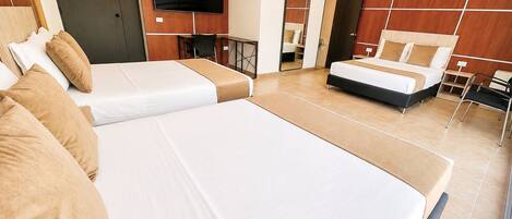 Habitación de hotel con dos camas, televisión, escritorio y espejo.