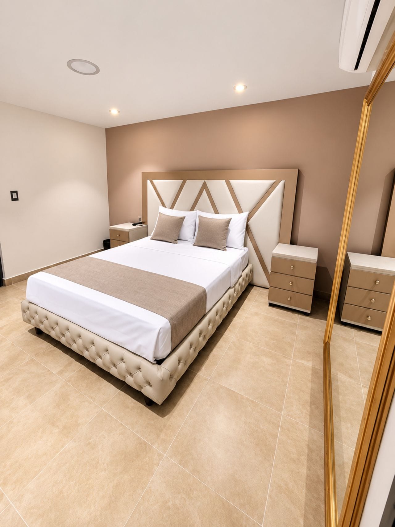 A modern bedroom with a large bed, bedside tables, and a built-in wardrobe.