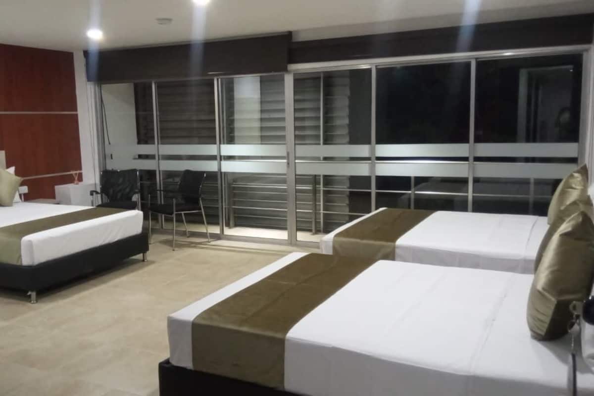 A hotel room with two beds, a large window, and a seating area with chairs.