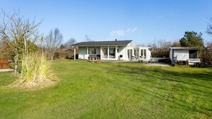 Ein eingeschossiges Haus mit Veranda, einer kleinen angebauten Garage und einem gepflegten Rasen.